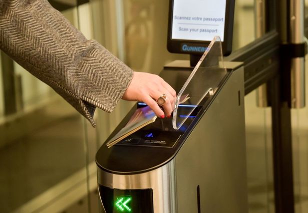 A woman scans her passport at an automated kiosk