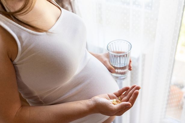 Maternal supplements pill. Happy smiling woman taking pill with supplement vitamin Omega 3. Pregnancy, medicine health care concept