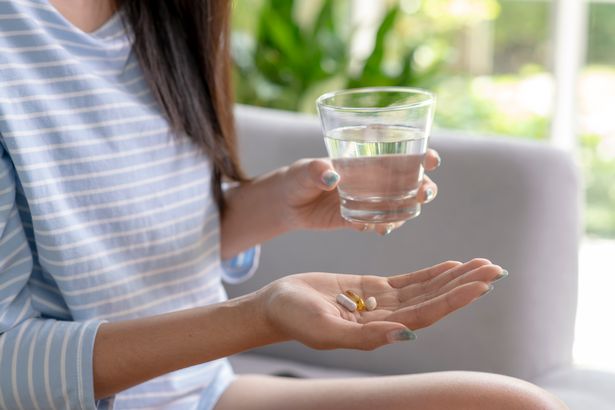 Young woman taking pill and vitamin in the living room.