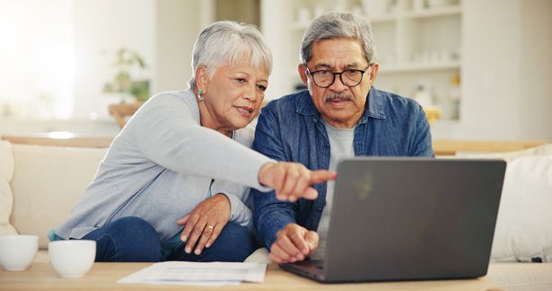 Senior, couple and pointing on laptop in living room with document for financial planning