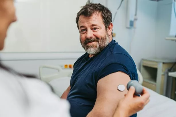 Doctor applying a blood glucose sensor to the patient's arm.