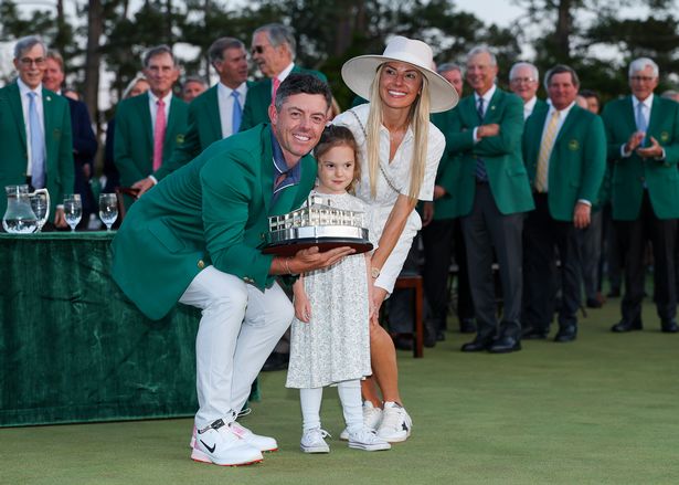 Rory McIlroy of Northern Ireland poses with daughter Poppy and wife Erica Stoll holding the Masters trophy during the Green Jacket Ceremony after winning the 2025 Masters Tournament at Augusta National Golf Club on April 13, 2025 in Augusta, Georgia. 