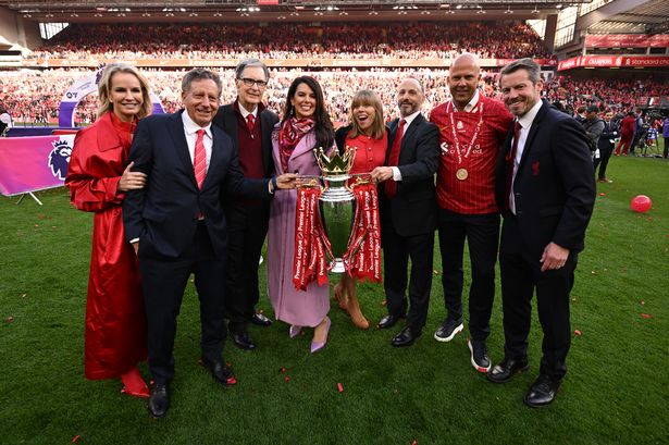 Key FSG and Liverpool FC figures including John Henry, Billy Hogan and Arne Slot pose for a photo with the Premier League trophy. 