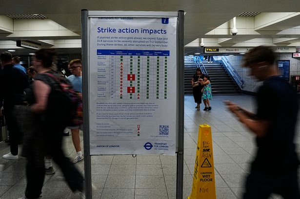 Passengers walking through a Tube station with a sign highlights all the impacts of the strike 