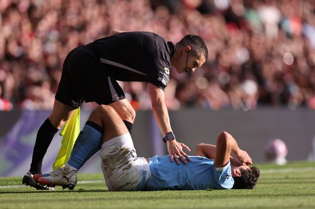 The assistant referee checks on Abdukodir Khusanov of Manchester City as he lies injured during the Premier League match between Arsenal and City