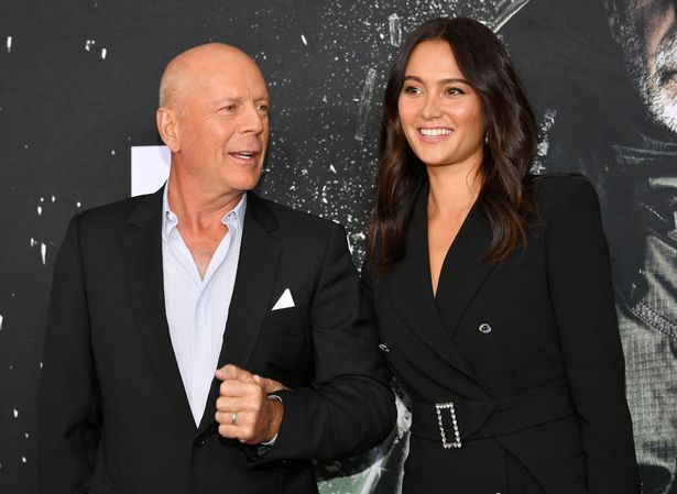 Bruce Willis and Emma Heming, both in black, on a red carpet in 2019.