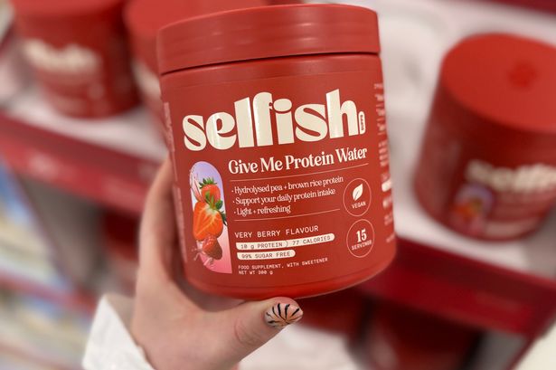 Woman holding Selfish Give Me Protein Water in Boots