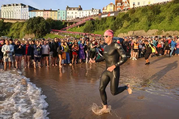 Man running into the sea with hundreds of spectators watching on