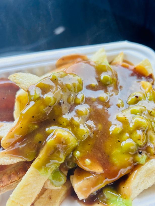 A close up of the meat and potato pie with gravy and peas