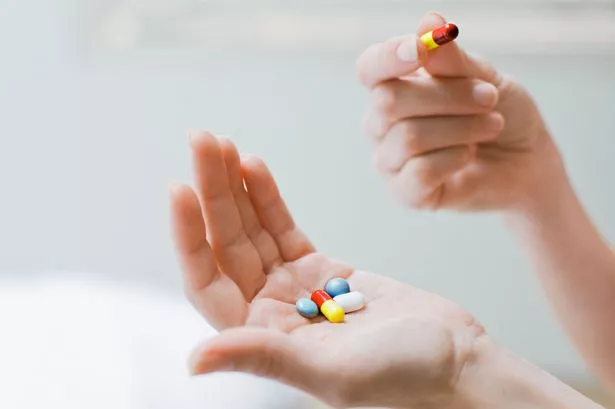 Person's hand holding a variety of medication