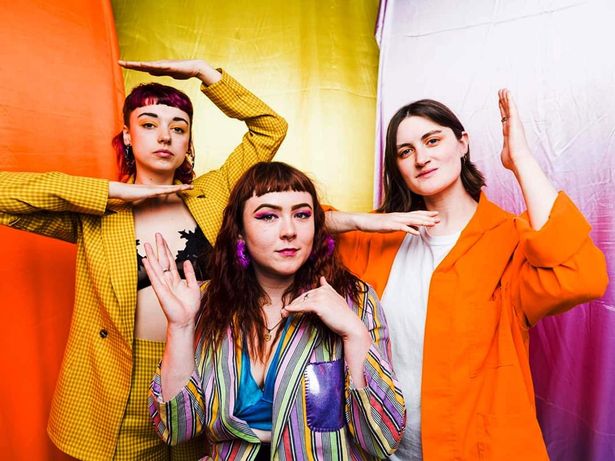 Three women in bright coloured clothing posing