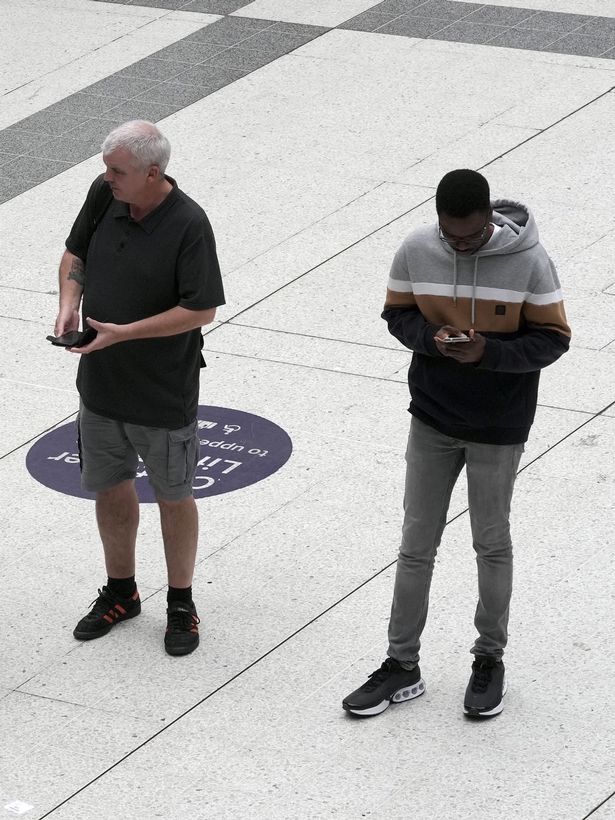 People look at their mobile phone in London Liverpool Street station