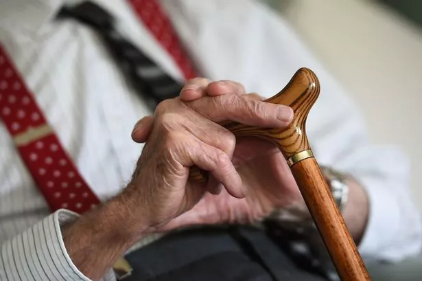 An elderly man holding a walking stick