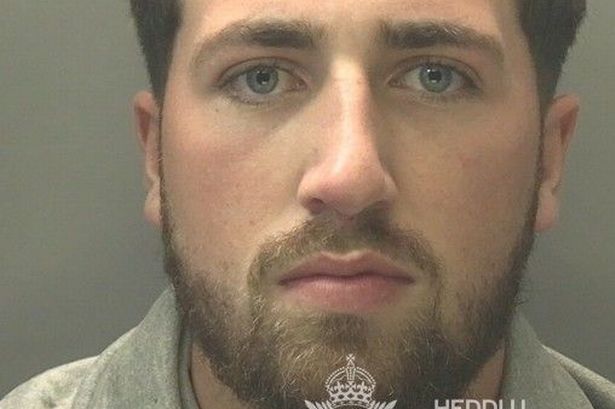 Custody photo of Tristan Turner, 27, who has short brown hair, a brown bears and is wearing a grey tracksuit.