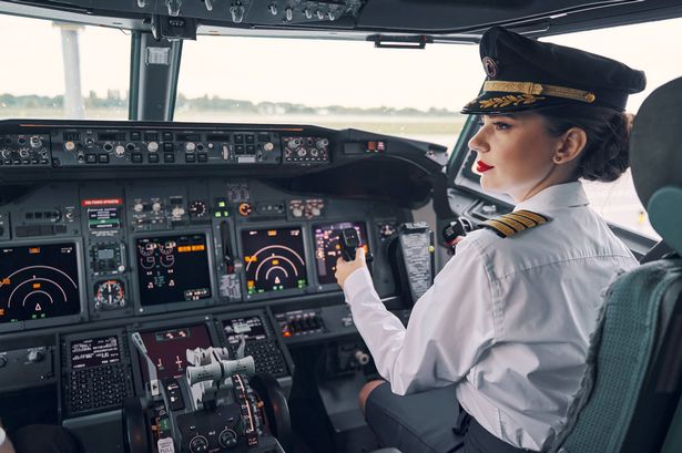 Back view of a thoughtful female first officer sitting at the control column in the flight deck