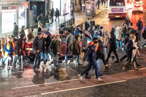 People crossing Hanover Street to continue on Princes Street in Edinburgh's city centre on a November evening.