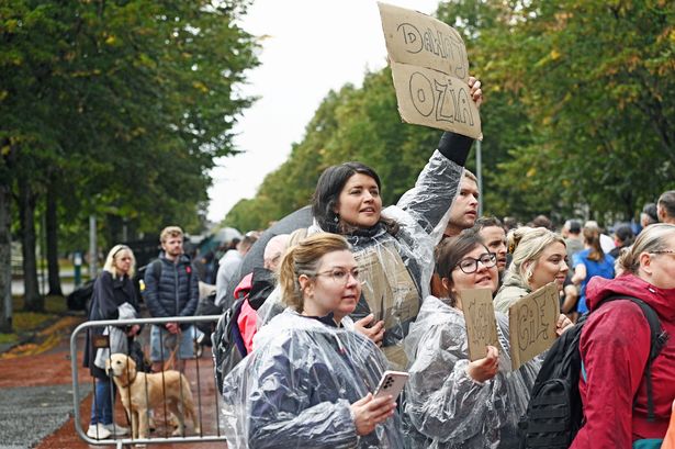 Spectators cheering on Cardiff 10K runners clad in raincoats 