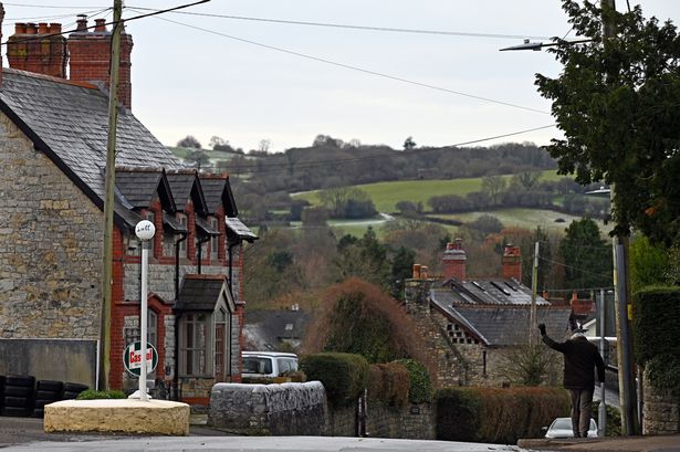The image shows Peterston-super-Ely - an archetypal old Welsh village - with a man to the side of the image waving with his back to the camera