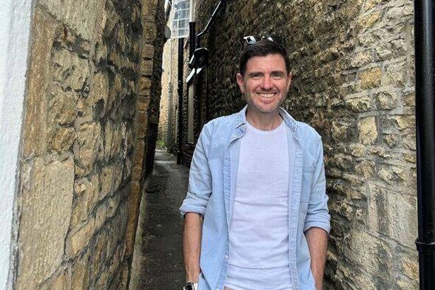 Steffan Rhys stands in one of Stow-on-the-Wold's historic tures, narrow alleys between buildings just about wide enough to stand in