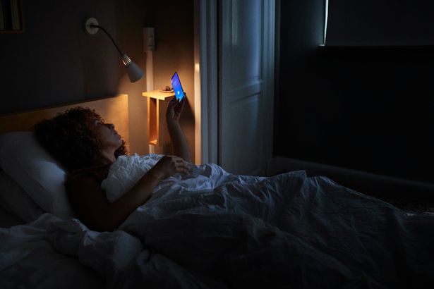 Woman scrolling through phone in bed