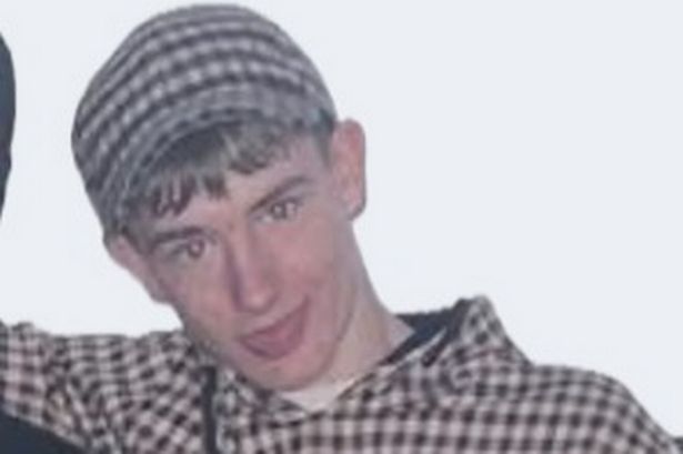 An image of a teenage boy wearing a brown checked hooded top and matching hat, sticking his tongue out.