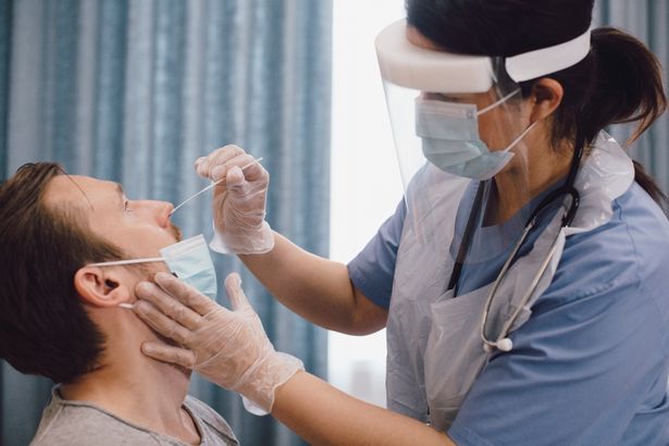 Man getting PCR Covid test, nurse in PPE