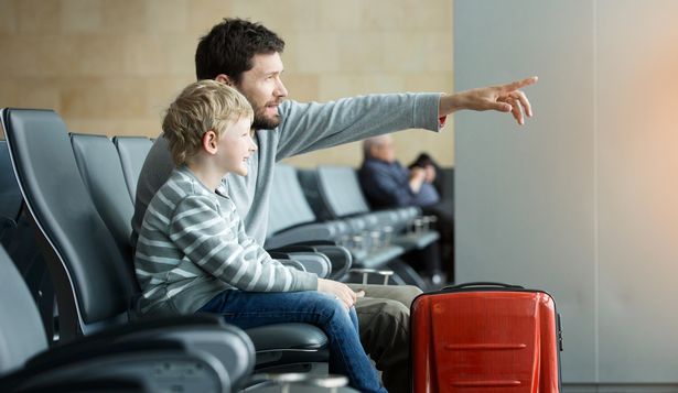 Getty generic. panorama of happy family of two, single father and son, waiting together at the airport for plane departure with luggage, father pointing with finger at something, sun flare effect