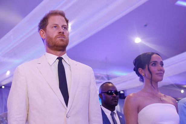 Prince Harry, Duke of Sussex, and Meghan, Duchess of Sussex at event dressed in white staring forward