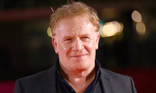 A man in black smiles 