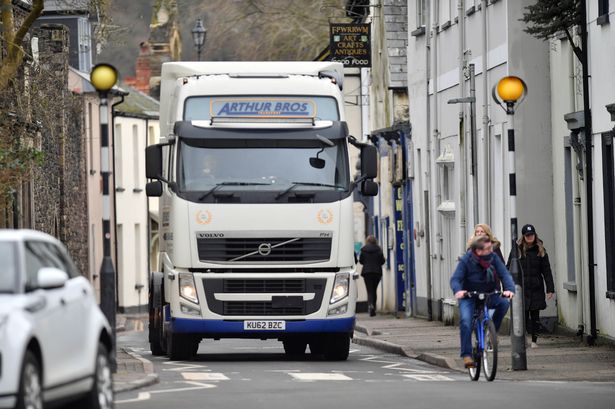 The image shows a lorry trying to navigate its way through the quaint small streets of Caerleon