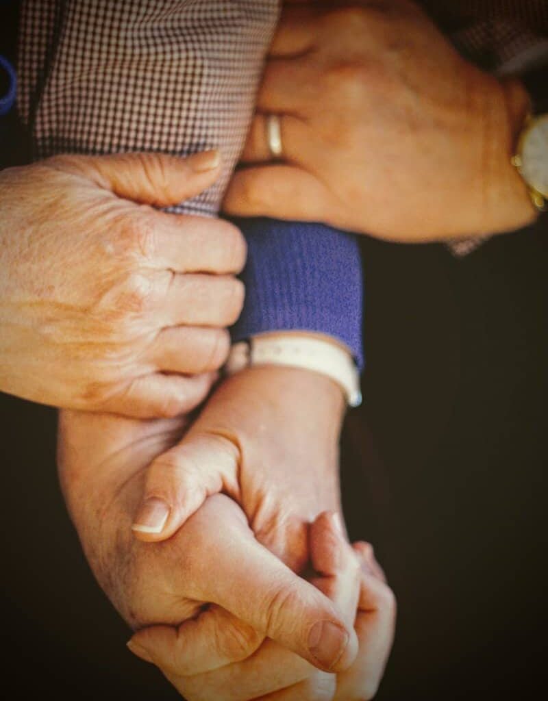 person in blue long sleeve shirt holding babys hand