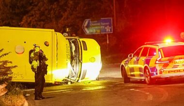 Two crew members inside the toppled and smashed-up ambulance (pictured) were rushed to hospital