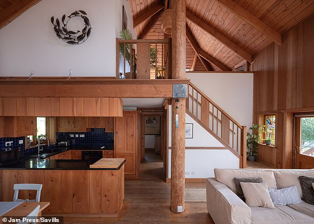 Its listing states: 'The open-plan main living room features a striking double-height vaulted beam ceiling and the sturdy timber poles central to the home's design'