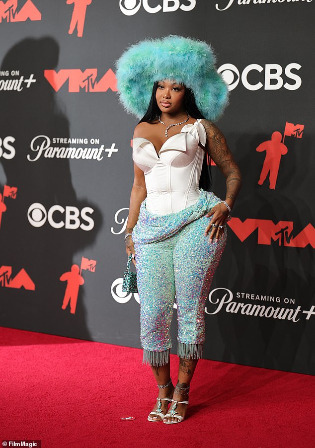 Summer Walker opted for sparkly blue pants with tassels at the bottom, a white corset top, and a huge fluffy hat. And when we say huge, we really mean huge