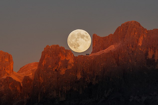 The Earth's tides are strongly influenced by the moon's gravitational pull, which causes our oceans to slosh in two bulges. Pictured: The moon over the Dolomites