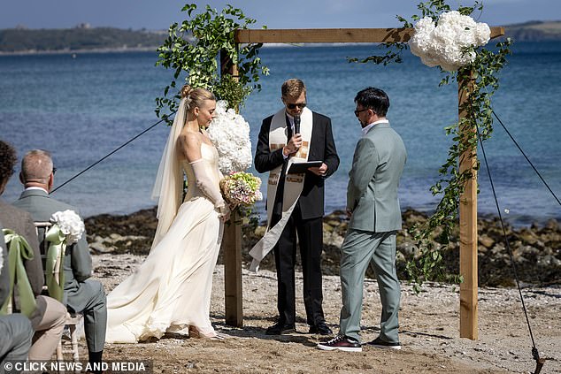 She held a stunning bouquet of hydrangeas as they stood under a wooden frame