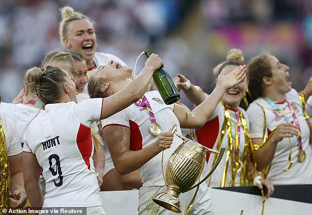 England's Zoe Aldcroft holds the trophy as she celebrates with Natasha Hunt who pours champagne on her