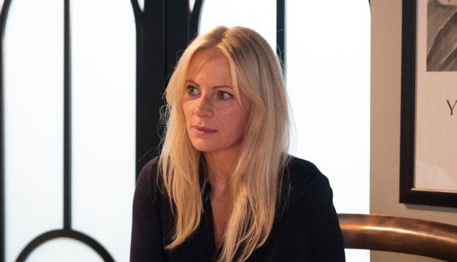 Lisa Swain sitting at the kitchen island looking stunned in Coronation Street.