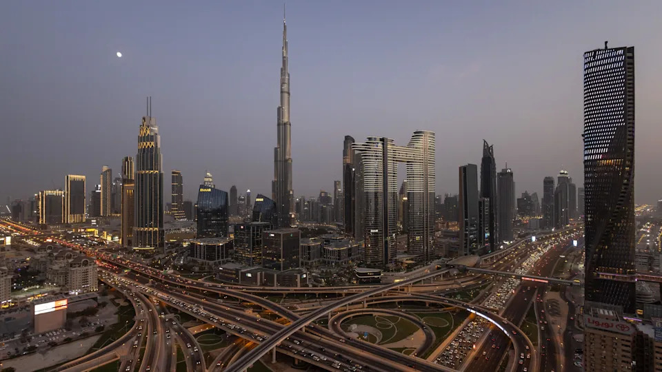 Wide shot of the Dubai skyline, taken at night. It features a number of striking, illuminated buildings, including the 828 metre (2,717 ft) Burj Khalifa, which has been the world's tallest building since 2009.