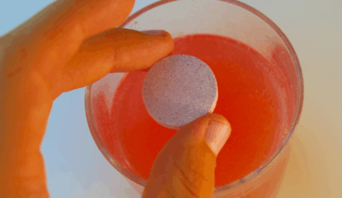 a person's hand dropping an electrolyte tab into a glass of water