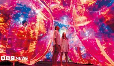 One of the installations at a previous Leeds Light Night festival. Two people stare up at glowing red and yellow spheres surrounding them.