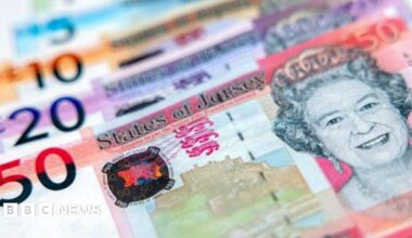 A picture of 4 States of Jersey bank notes. They are red, purple, orange and blue in colour. There is a picture of the queen on the right of the notes.