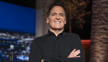 Mark Cuban in a black shirt on set smiling with his arms crossed
