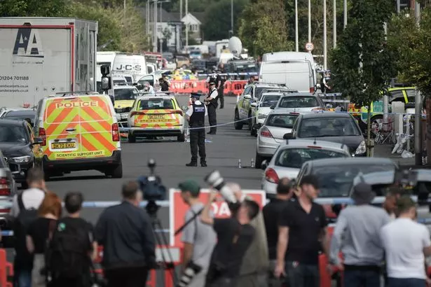 Press stand behind a police cordon on the day of the attack
