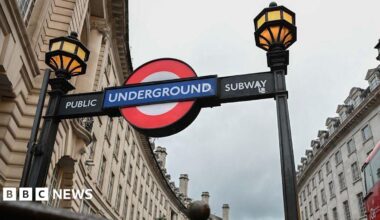 The entrance to a London Underground subway, with the red, whit ea blue Underground logo and yellow lamps.