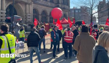 The demo outside Sheffield Town Hall, with people waving red Unite banners, balloons and flags.