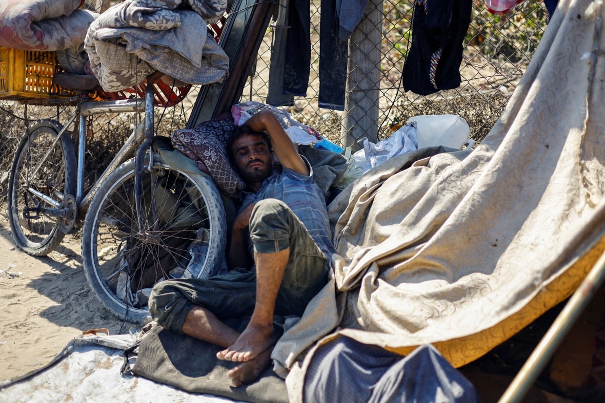 A man lies on the ground next to his belongings.