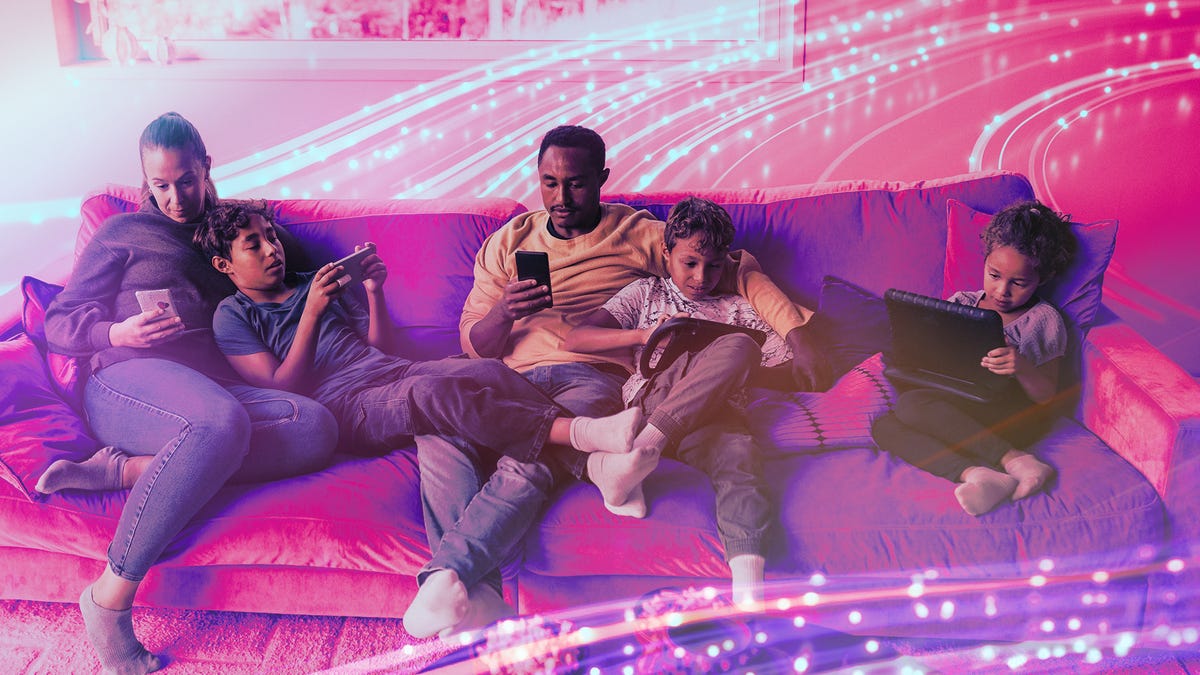 Family sitting on a couch browsing on their phones and tablets.