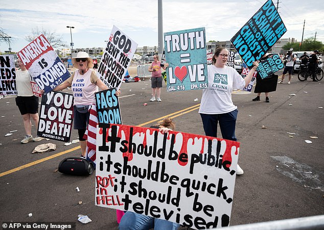 A protester against the Charlie Kirk memorial sits in front of members of the Westboro Baptist Church protesting outside the memorial for Charlie Kirk at State Farm Stadium in Glendale, Arizona on September 21, 2025. (Photo by ANDREW CABALLERO-REYNOLDS / AFP) (Photo by ANDREW CABALLERO-REYNOLDS/AFP via Getty Images)