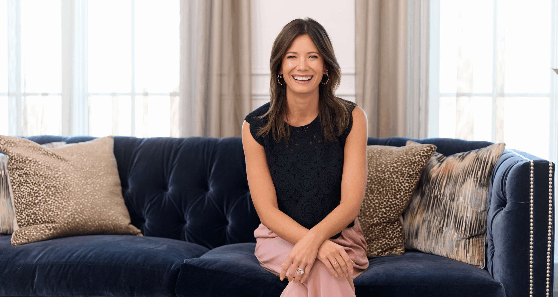 Image of Rachel Cruze smiling while sitting on blue couch